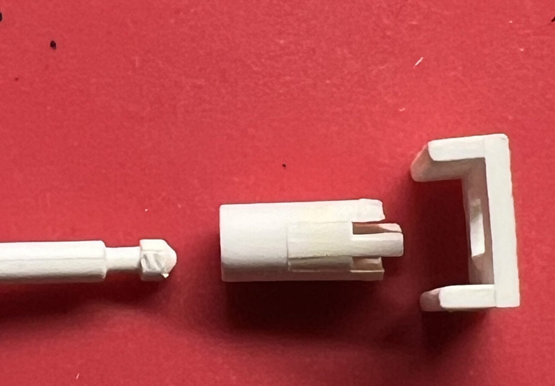 Drei Teile - der Knopf mit dem Stift links, das abgebrochene Fassungs-Teil in der Mitte, und die Oberplatte rechts